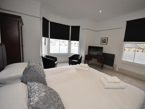 a bedroom with a white bed with two chairs and a desk at The Chapel House in Scarborough
