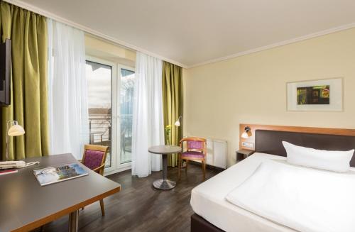 a hotel room with a bed and a desk at Seminaris SeeHotel Potsdam in Potsdam