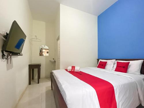 - une chambre avec un grand lit et une couverture rouge et blanche dans l'établissement RedDoorz Syariah @ Pahlawan Sidoarjo, à Sidoarjo