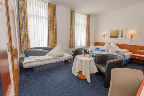 una camera d'albergo con due letti e un tavolo con sedie di Inselhotel Cornelius a Norderney
