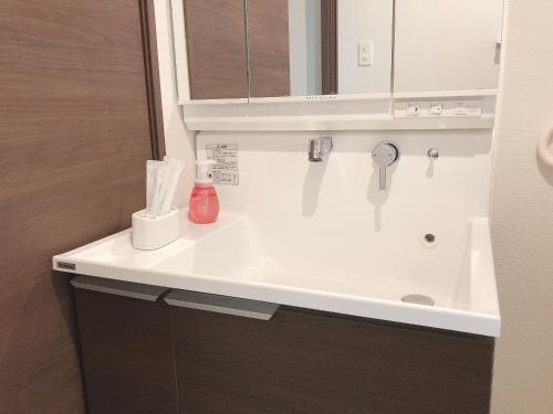 y baño con lavabo blanco y espejo. en TerraceRin YN23, en Tomigusuku