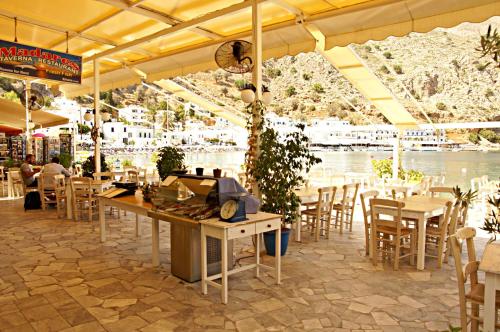 um restaurante com mesas e cadeiras e vista para a água em Αnna em Loutró