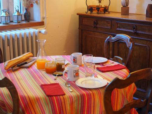 einen Tisch mit gestreiftem Tischtuch und Orangensaft darauf in der Unterkunft La grange in Alluyes