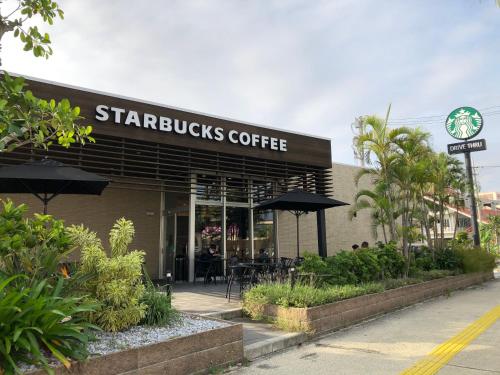 a starbucks coffee building with tables and umbrellas at TerraceRin YN23 in Tomigusuku