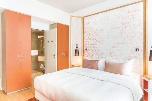 a bedroom with a large white bed and orange cabinets at Capri by Fraser Berlin in Berlin