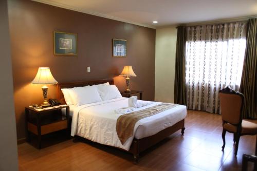 a bedroom with a bed and two lamps and a window at Crown Royale Hotel in Balanga