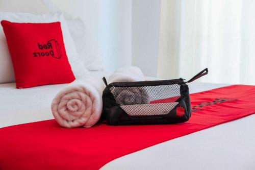 a red blanket and a bag on a bed at RedDoorz Plus near Soekarno Hatta Airport Taman Mahkota in Tangerang