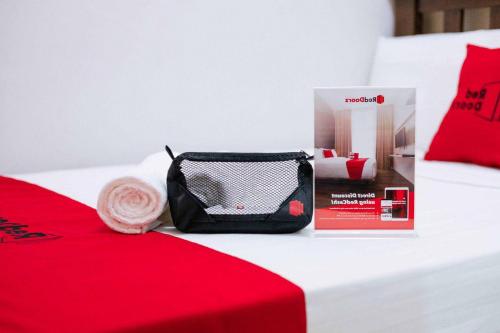 a red bed with a bag and a box on it at RedDoorz Plus near Soekarno Hatta Airport Taman Mahkota in Tangerang