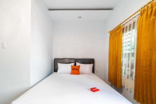 a bedroom with a bed with an orange pillow on it at RedDoorz Plus near Soekarno Hatta Airport Taman Mahkota in Tangerang