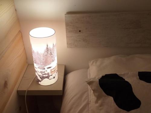 una lámpara sentada en una mesa junto a una cama en Chalet Plein Sud en Montgenèvre