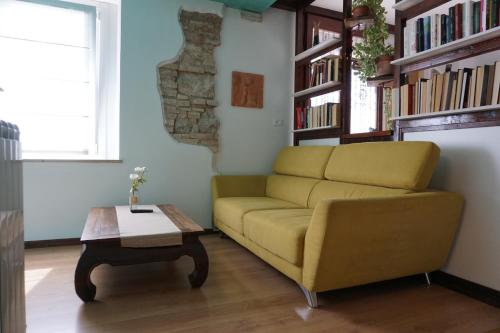 a living room with a yellow couch and a coffee table at A Casa Mia in Romàns dʼIsonzo