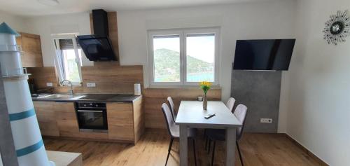 a kitchen with a table and chairs and a kitchen with a window at Apartmani Tisno TM in Tisno