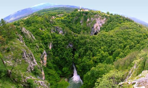 a mountain with a waterfall and trees on it at HOSTEL-SezanaLOKEV B&B in Sežana