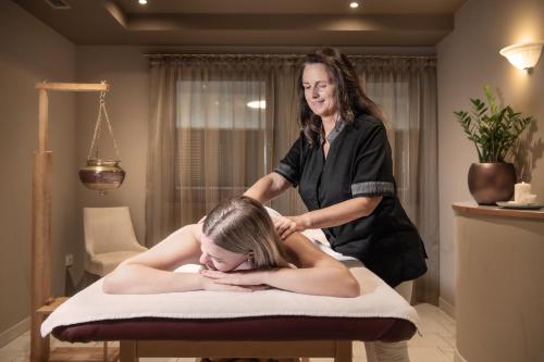 a woman getting a massage from a therapist at Small & Beautiful Hotel Gnaid in Tirolo