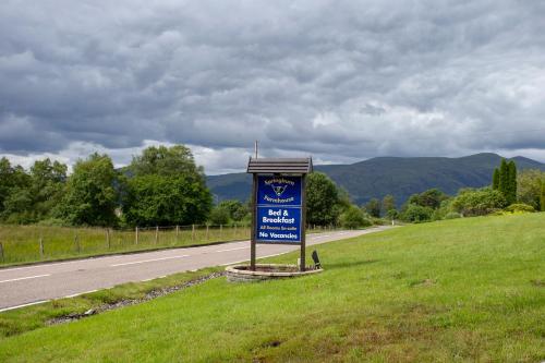 a blue sign on the side of a road at Springburn Farmhouse in Spean Bridge