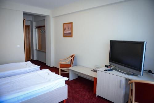 a hotel room with a tv and a bed and a desk at Pension Panorama in Odorheiu Secuiesc