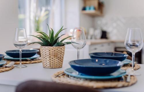 a table with wine glasses and plates and a plant at Nádas Center Home Badacsony in Badacsonytomaj