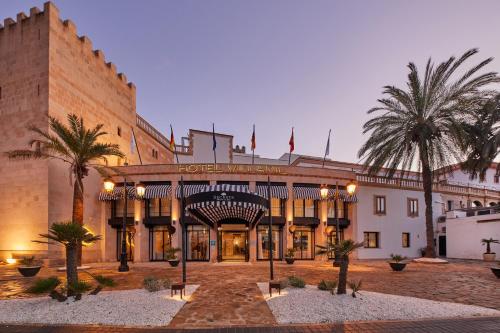 a large building with palm trees in front of it at Secrets Mallorca Villamil Resort & Spa - Adults Only (+18) in Paguera