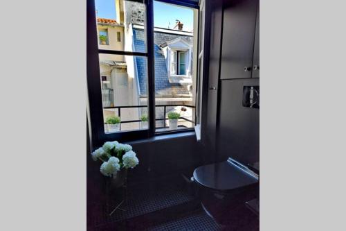 a bathroom with a window and a vase of flowers at Le Boudoir in Lyon