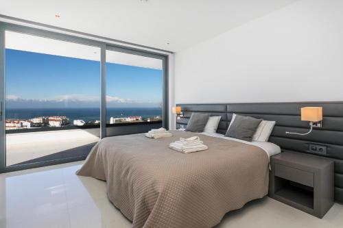een slaapkamer met een bed en een groot raam bij The Villa / Ericeirahills in Ericeira