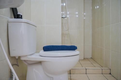a bathroom with a toilet with a blue towel on it at New Furnished 2BR Apartment at Serpong M-Town Residence By Travelio in Tangerang