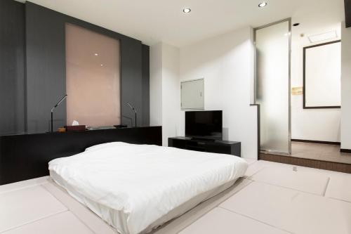 a bedroom with a white bed and a television at THE MANGA HOTEL TOGO in Togo