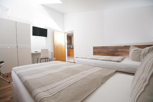 a white bedroom with two beds and a television at Apartment Hohenstaufen in Göppingen