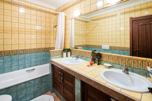 a bathroom with two sinks and a tub and a mirror at Terraços de Benagil 23 (Casa Alvorada) in Benagil
