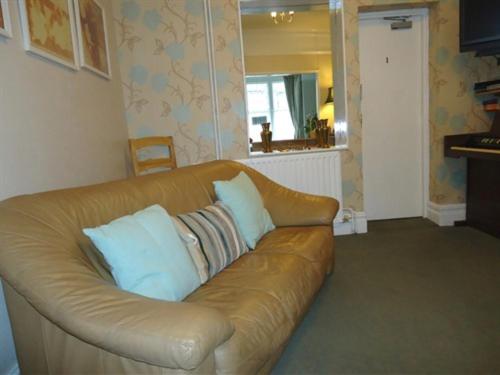 a brown leather couch with pillows in a living room at Rob Roy Guest House in Folkestone