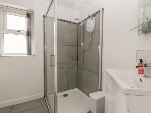 a white bathroom with a shower and a sink at Cartrefle Fach in Pentraeth