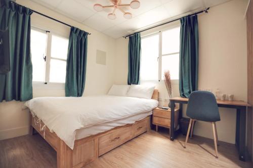 a bedroom with a bed and a desk with a chair at Yua Ya B&B in Tainan