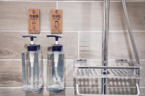 two bottles of toothbrushes on a wall in a bathroom at Yua Ya B&B in Tainan