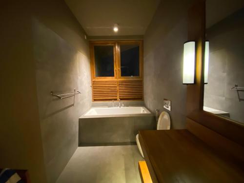 a bathroom with a tub and a toilet and a window at Atulya Villas Nuwara Eliya in Nuwara Eliya