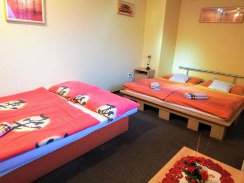 2 Betten in einem Zimmer mit roter Bettwäsche in der Unterkunft Restaurant-Penzión HEVIL in Hlučín