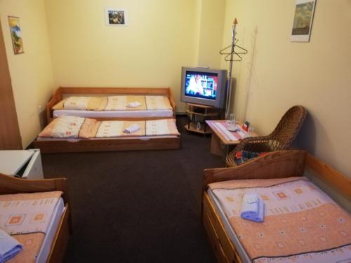 a room with three beds and a tv at Restaurant-Penzión HEVIL in Hlučín