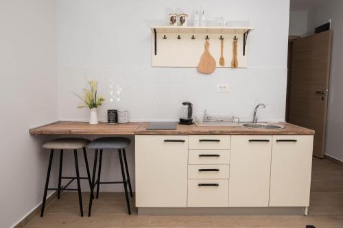 ポドゴリツァにあるStudio apartment Vukcevic 2の白いキャビネット、シンク、スツール付きのキッチン