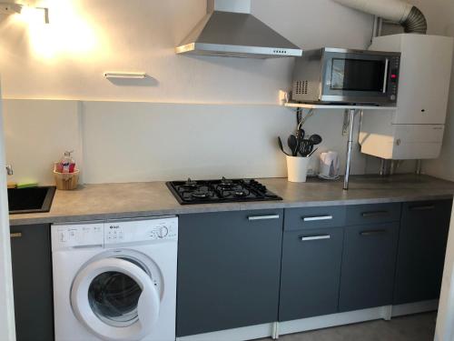 eine Küche mit einer Waschmaschine und einer Mikrowelle in der Unterkunft Les Appartements Chambon in Sarlat-la-Canéda