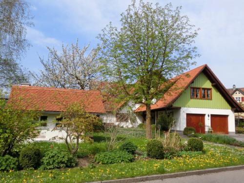 a green and white house with a red roof at Ferienwohnung Hahn in Weißensberg