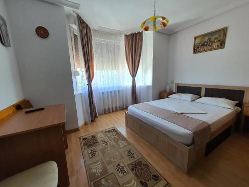 a bedroom with a bed and a desk and window at Pensiunea Stan in Cisnădie