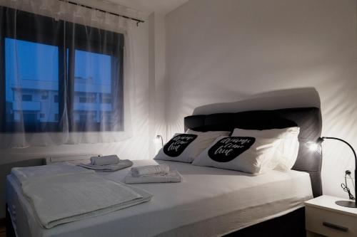 ein weißes Bett mit weißen Kissen und einem Fenster in der Unterkunft Apartmans Centar in Trebinje