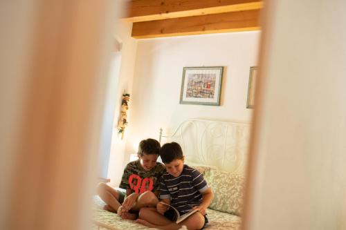 two boys sitting on a bed reading a book at Villa Vitis in Negrar