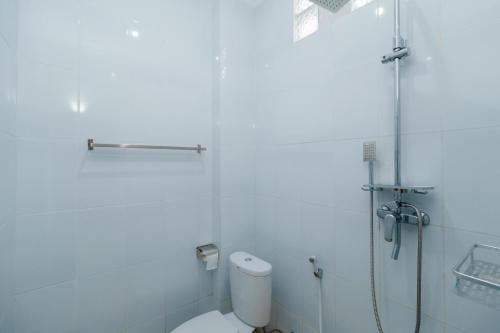 a white bathroom with a shower and a toilet at Reddoorz near Universitas Widyagama Malang 2 in Malang