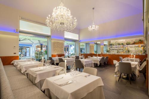 a restaurant with white tables and chairs and chandeliers at Best Western Hotel Nazionale in Sanremo