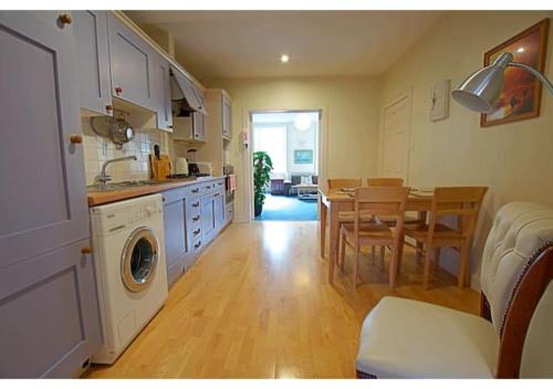 uma cozinha com uma máquina de lavar roupa e uma sala de jantar em ALTIDO Gorgeous 2-bed flat near Edinburgh Castle em Edimburgo