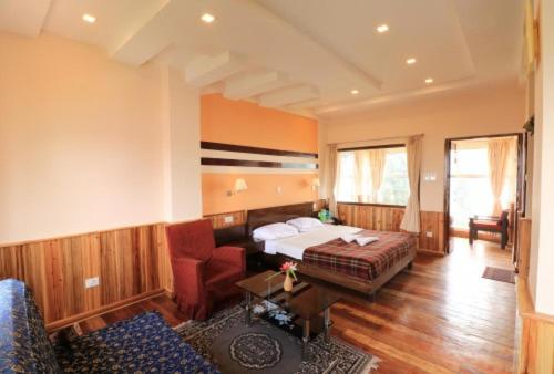 ダージリンにあるDarjeeling Tourist Lodgeのベッドとソファ付きのホテルルーム