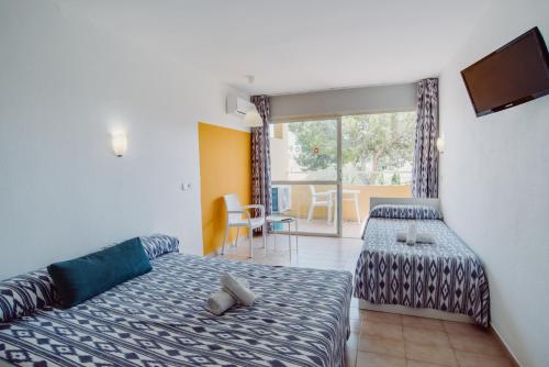 パルマノヴァにあるAlper Apartments Mallorcaのベッドとテレビが備わるホテルルームです。