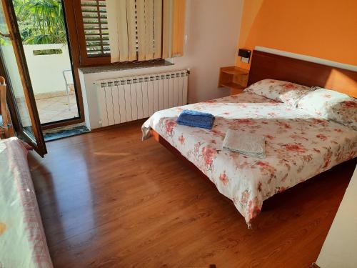 a bedroom with a bed and a wooden floor at Apartments Bogdi in Draga Bašćanska