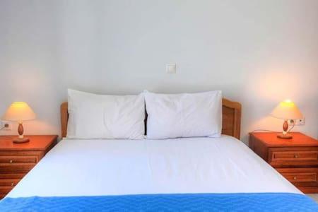 a bedroom with a large bed with two night stands at Saint Nicholas Katapola in Katapola