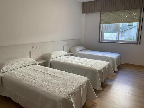 Habitación hospitalaria con 3 camas y ventana en Apartamento Salomé, en Padrón