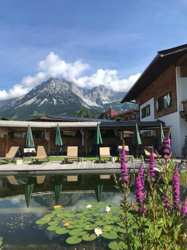 a resort with a pool with a mountain in the background at Flora - Das kleine Gartenhotel in Ellmau